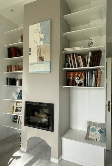 Bibliothèque blanche avec cheminée et peinture moderne