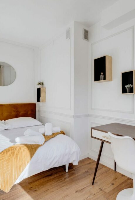 Chambre lumineuse avec lit double, bureau et accents dorés