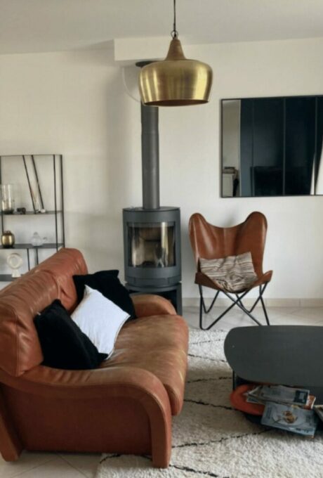 Salon confortable avec canapé en cuir, poêle à bois et fauteuil