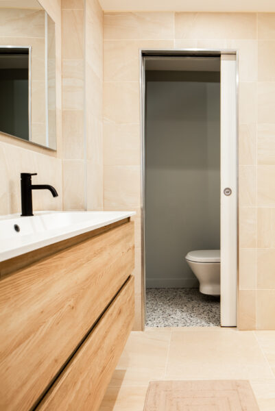 Lavabo avec meuble en bois clair et vue sur wc