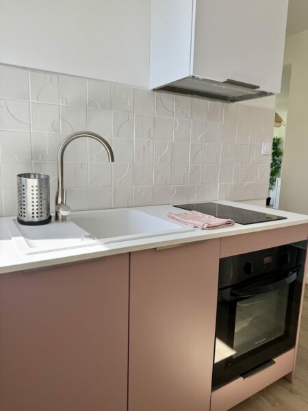 Cuisine moderne avec évier, robinet, plaque de cuisson, four, dosseret blanc, armoires roses, architecte intérieur toulouse