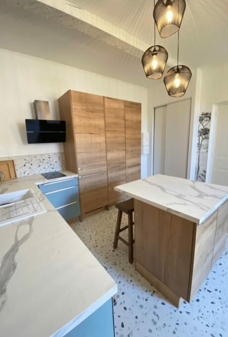 Cuisine moderne avec armoires en bois, plans de travail en marbre et suspensions