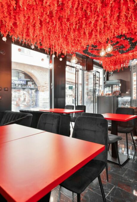 Intérieur de restaurant contemporain avec tables rouges et décorations au plafond