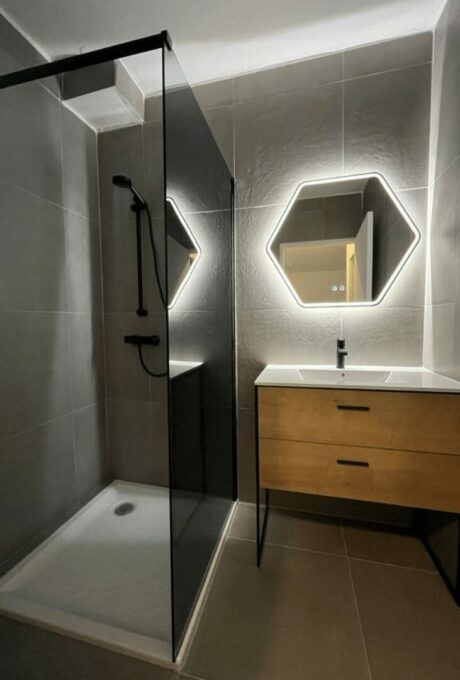 Salle de bain moderne avec miroirs hexagonaux, douche noire et meuble-vasque en bois