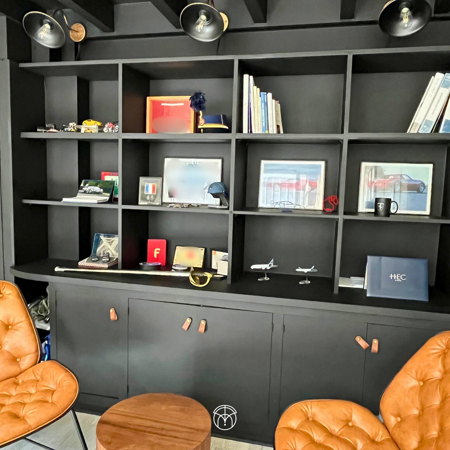Étagère moderne avec objets décoratifs, livres, tableaux, chaises en cuir.