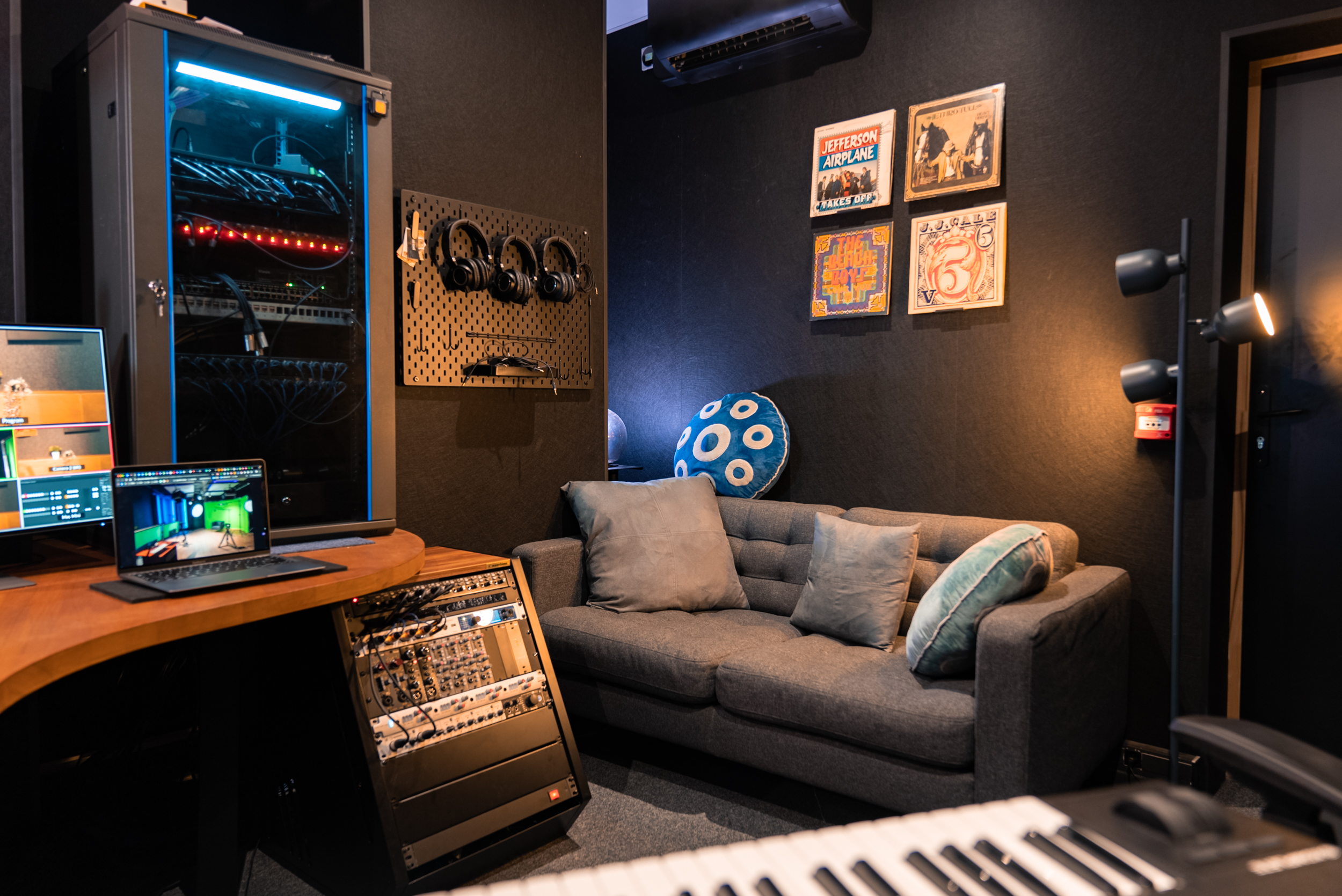 Studio de musique avec ordinateur, clavier, canapé et équipements audio.