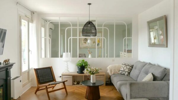 Salon moderne avec canapé, chaise, table basse, plantes, miroir, lampe, intérieur design.
