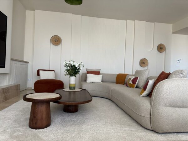 Salon moderne avec canapé, tables basses, fleurs, éclairage mural, décoration intérieure.