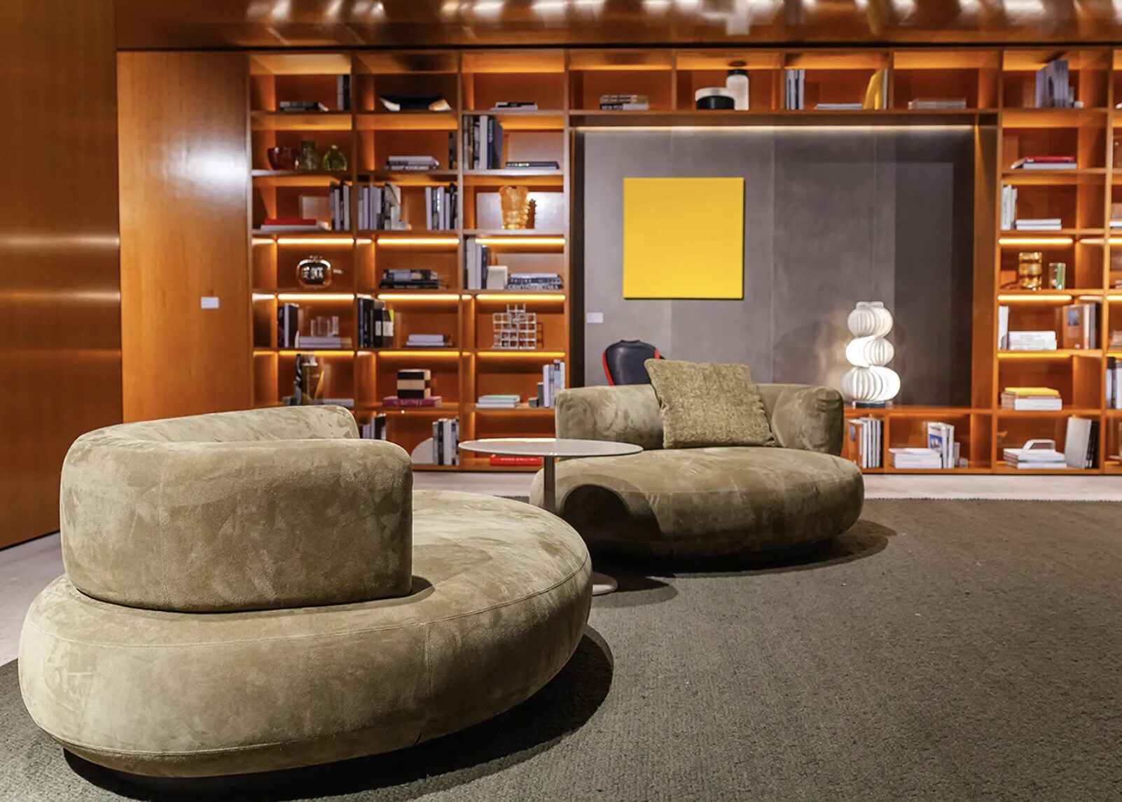 Salle de lecture moderne avec canapés ronds et bibliothèque.